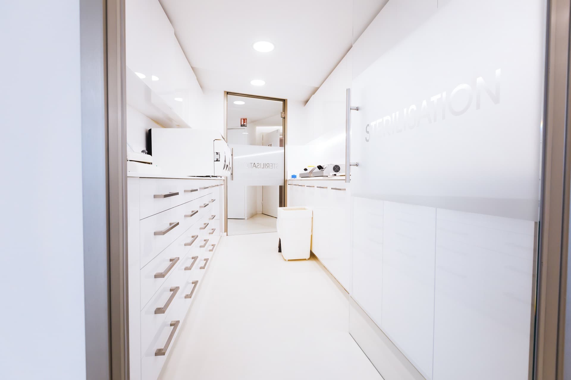 Bright white clinic corridor leading to treatment rooms