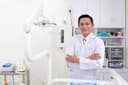 Man dentist in a white coat standing with his arms crossed