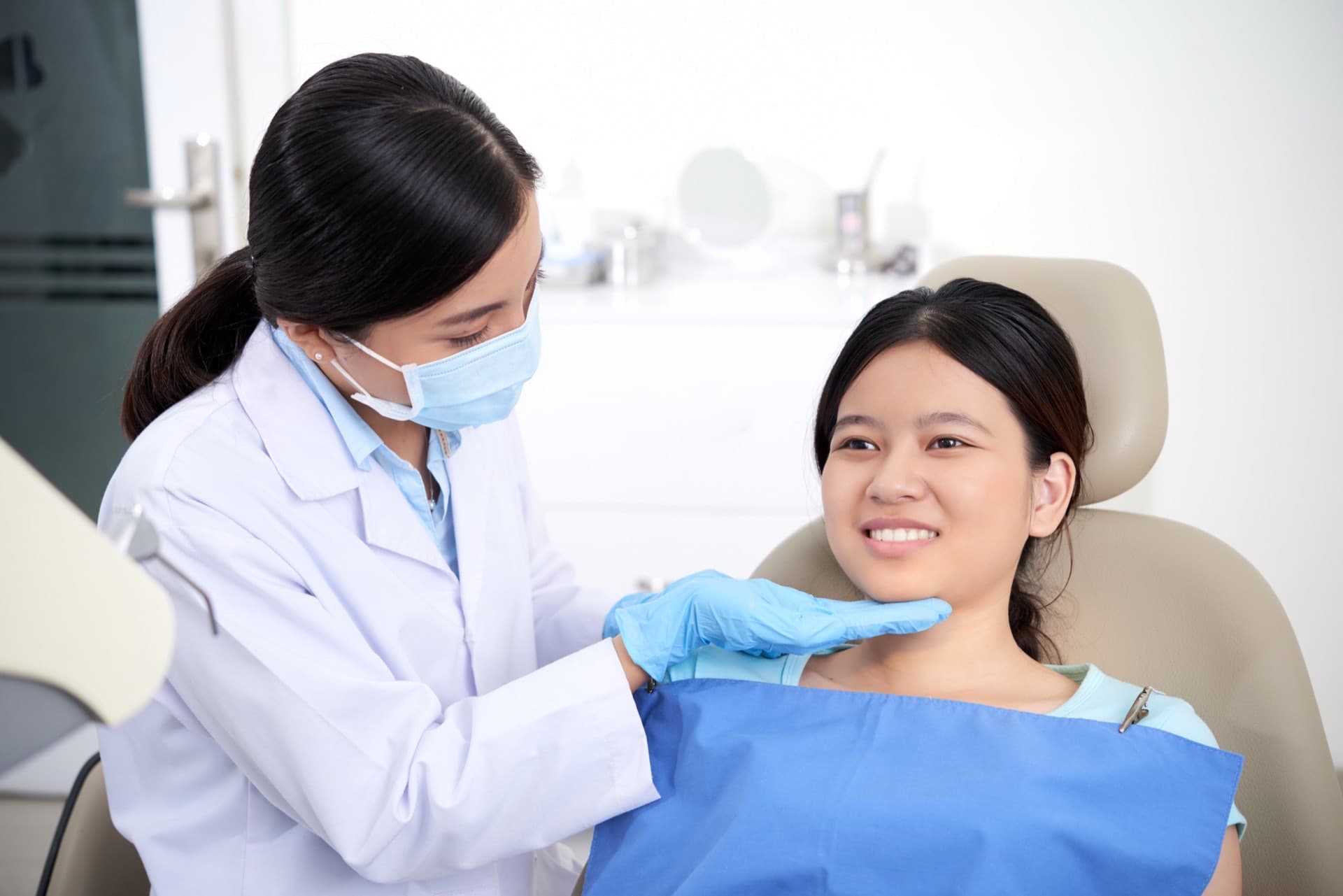 Dentist standing beside a smiling patient seated in a dental chair